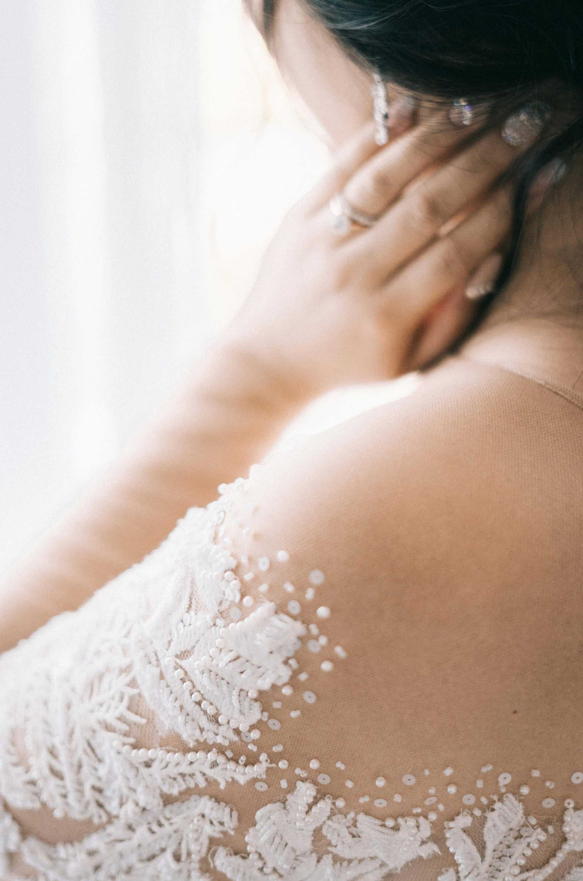 Bride's lace gown and jewelry, with soft focus on intricate fabric details.