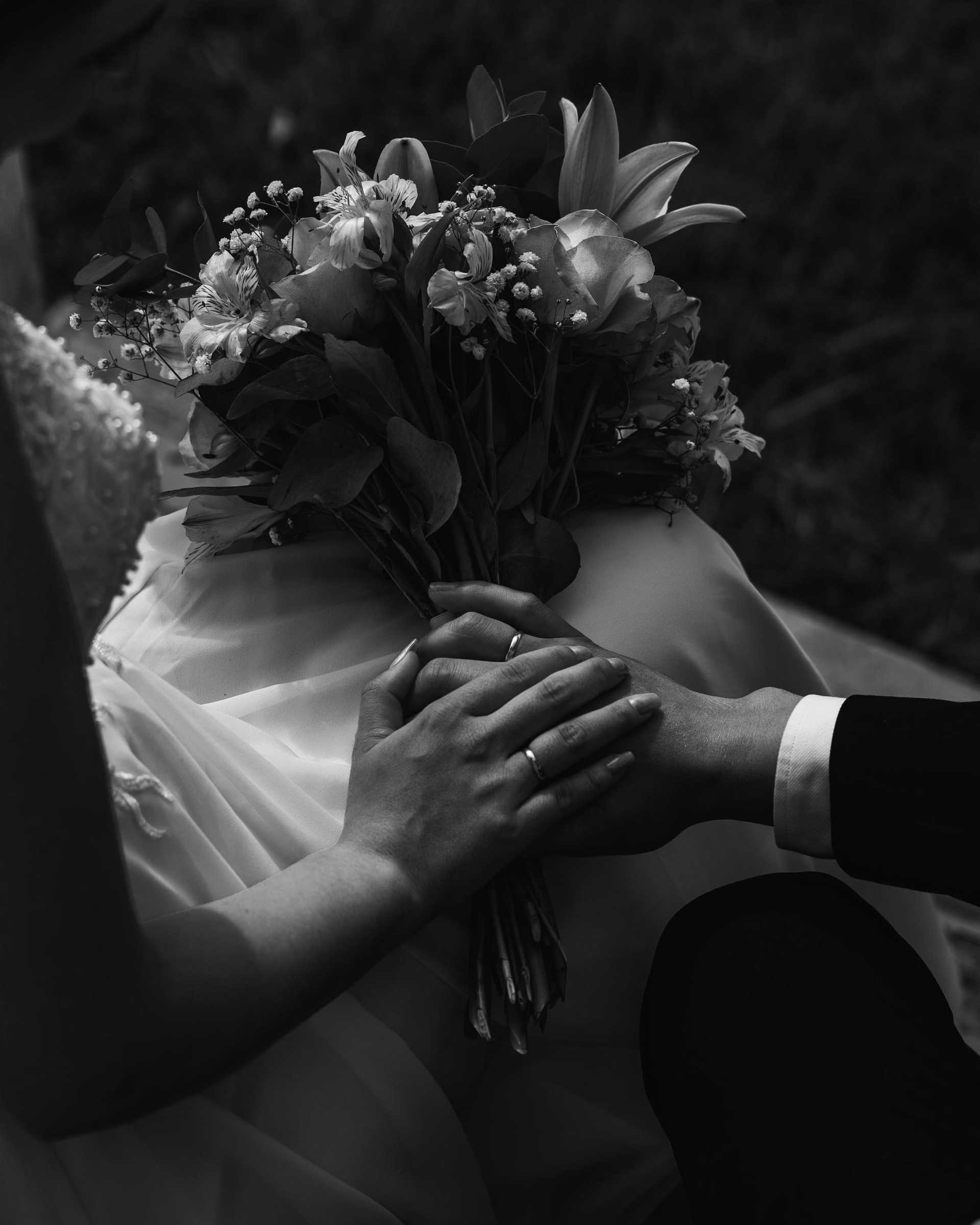 Bride and groom holding hands, with bouquet, in a tender moment.